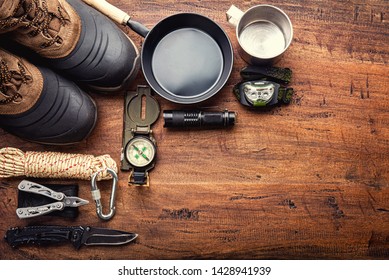 Outdoor travel equipment planning for a mountain trekking camping trip on wooden background. Top view - vintage film grain filter effect styles