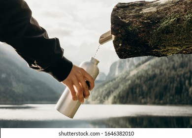 Outdoor Travel Water Bottle: A Man's Hand Dials Water From A Water Source Into A Bottle. Pure Natural Water.