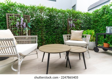 Outdoor veranda of house with brown wicker armchair and plants pots. Cozy space in patio or balcony with garland. Modern lounge outdoors in backyard. - Shutterstock ID 2247865403