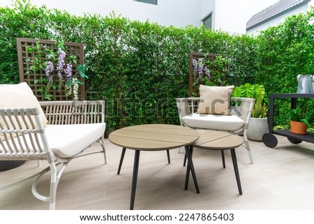 Outdoor veranda of house with brown wicker armchair and plants pots. Cozy space in patio or balcony with garland. Modern lounge outdoors in backyard.