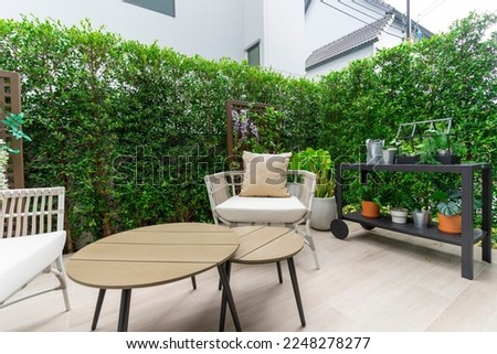 Outdoor veranda of house with brown wicker armchair and plants pots. Cozy space in patio or balcony with garland. Modern lounge outdoors in backyard.