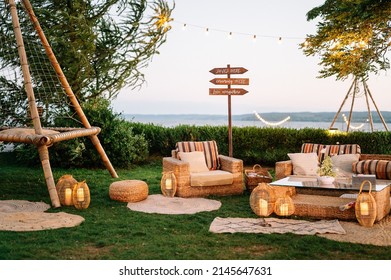 Outdoor wedding. Banquet. signs on wooden board decorated by flowers and greenery and lounge zone in boho style including chairs and tables. - Shutterstock ID 2145647631