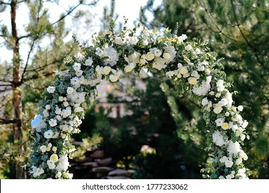 Outdoor wedding ceremony setup, wedding arch decorated with pastel white flowers