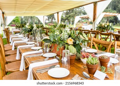 An outdoor wedding ceremony venue with arranged wooden tables