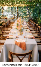 outdoor wedding. long banquet tables with white tablecloths , on the tables are flower arrangements, candles, plates with napkins, glasses and cutlery in autumn style