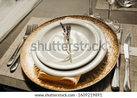 Outdoor wedding and romantic table setting in rustic style on wooden table. Plates, vintage silverware, blank rough tag and lavender flowers.