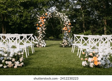 Outdoor wedding setup with floral arch. Wedding aisle with white wooden chairs. - Powered by Shutterstock