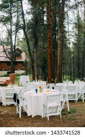 Outdoor Wedding Setup With White Tables And Chairs In The Forest. Forest Wedding Venue