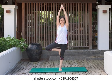 Outdoor, Wide Shot Portrait Of Asian Woman In Sportswear, Standing On Yoga Mat, Practicing Tree Pose At Outdoor Oriental Style Balcony. Sport, Fitness, Relaxation, Leisure Activity, Lifestyle Concept.