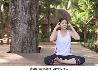 Outdoor, Wide Shot Portrait Of Young Asian Woman In Sportswear Sitting Under Big Tree, Practicing Yoga, Making Funny Face, Thinking. Meditation, Mindful, Well-being, Leisure Concept.