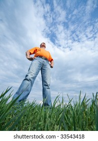 Outdoor Wide-angle Portrait Of A Tall Man In Jeans On Blue Sky And Green Grass Background