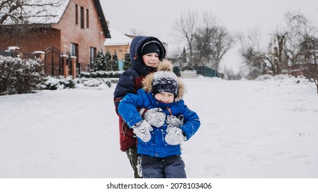 Outdoor Winter Activities For Kids. Kids Playing In The Suburbs, Winter Backyard Gathering. Boys Having Fun With Snow. Selective Focus