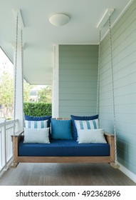 outdoor wooden porch swing bench with blue pillows.