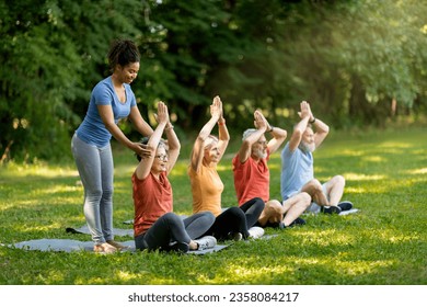 Outdoor Yoga Class. Group of smiling senior people training together outdoors, happy mature men and women in sportrswear sitting in lotus position with hands above head, enjoying healthy lifestyle - Powered by Shutterstock