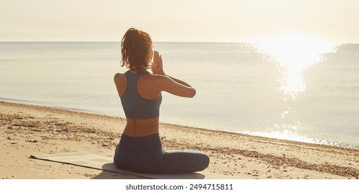 Outdoor yoga fitness woman practices meditation on a beach at sunrise, facing the ocean and embracing the tranquility of the moment. Ideal for promoting wellness, mindfulness, and beachside relaxation - Powered by Shutterstock