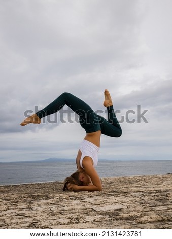 Outdoor yoga practice near the ocean. Young woman practicing Salamba Shirshasana, Yoga Headstand is an inverted asana. Beautiful asana. Healthy lifestyle. Yoga retreat. Copy space. Bali, Indonesia