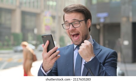 Outdoor Young Businessman Celebrating on Smartphone