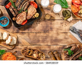 Outdoors Food Concept. Appetizing Barbecued Steak, Sausages And Grilled Vegetables On A Wooden Picnic Table With Copy Space, Top View