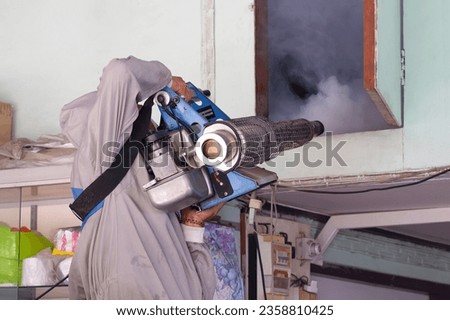 Outdoors Healthcare Worker in Protective clothing is Spraying Chemical to Eliminate mosquitoes into the door of attic room, close up with copy space
