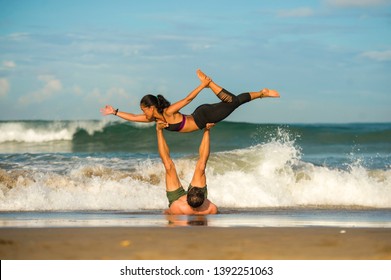 outdoors lifestyle portrait young attractive and concentrated couple of yoga acrobats practicing acroyoga balance and meditation exercise on beautiful beach in mind and body teamwork control - Shutterstock ID 1392251063