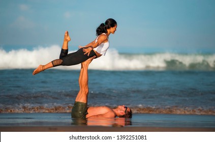 outdoors lifestyle portrait young attractive and concentrated couple of yoga acrobats practicing acroyoga balance and meditation exercise on beautiful beach in mind and body teamwork control - Shutterstock ID 1392251081