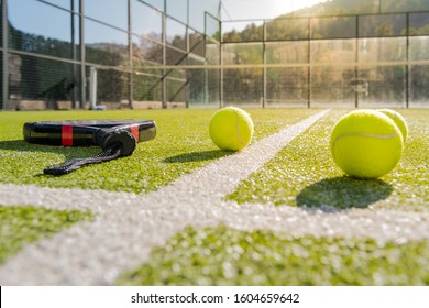 outdoors paddle tennis court with racket and yellow balls on the artificial turf at sunset, indoor sports concept and sporty lifestyle