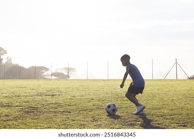 Outdoors, Playing soccer on school field, boy dribbling ball in morning sunlight. sports, children, teamwork, exercise - Powered by Shutterstock