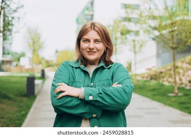 Outdoors portrait of beautiful young woman posing with arms crossed on street. 30s cheerful woman tourist dressed in casual look resting outdoors. Urban, people concept. High quality photo - Powered by Shutterstock