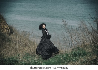 Outdoors portrait of a victorian lady in black. Run away and turned her head.