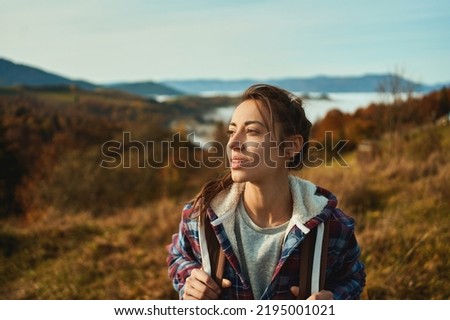 Outdoors portrait young millennial backpacker woman looking away, relaxing in nature during hiking by mountains range