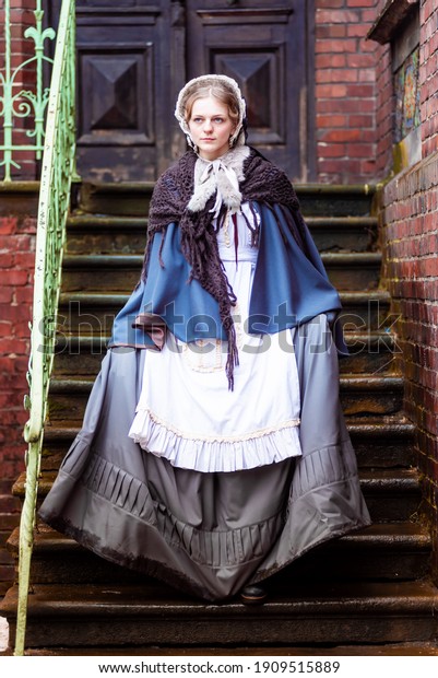 Outdoors portrait of a young victorian woman walking\
old city