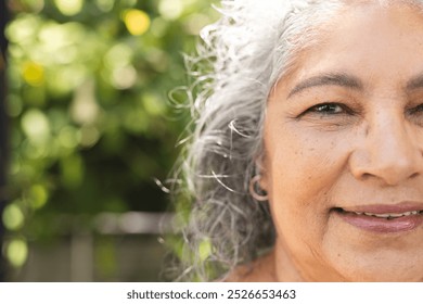 Outdoors, senior biracial woman with gray hair smiling, copy space. She, having light skin with visible wrinkles and dark eyes, wearing a warm sweater, unaltered - Powered by Shutterstock