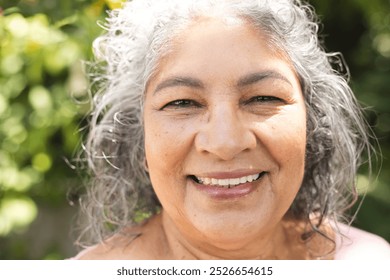 Outdoors, senior biracial woman with grey hair smiling. She has light brown skin, visible wrinkles, and dark eyes, enjoying fresh air, unaltered - Powered by Shutterstock