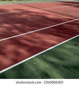 Outdoors tenniscourt a sunny day.Green and red hardcourt. 