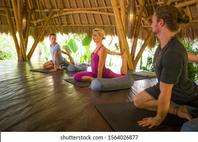 Outdoors Yoga Lesson - Group Of Young People And Coach Woman Practicing Relaxation Exercise At Asian Wellness Retreat Hut Training Body And Mind Balance Together In Harmony