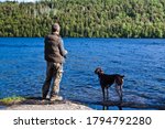 Outdoorsmen with his German shorthair pointer dog fishing at the lake 