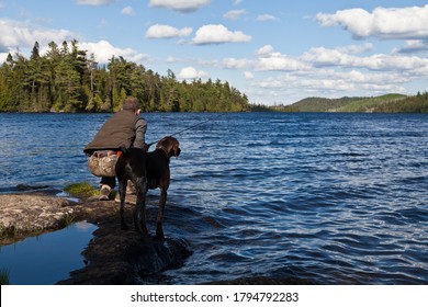 Outdoorsmen with his German shorthair pointer dog fishing at the lake  - Powered by Shutterstock