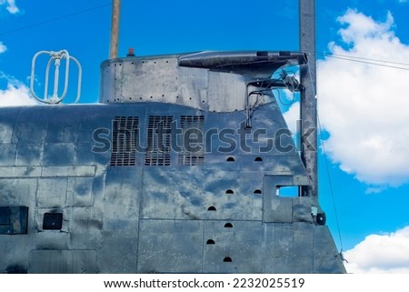 The outer part of the cabin of an old black metal submarine sticking out of the water.
