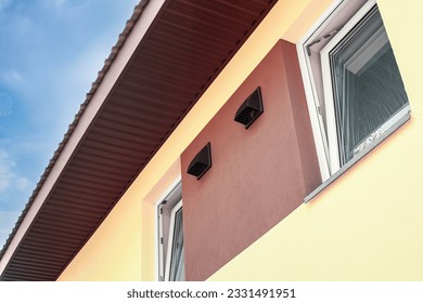 The outer side of the wall of the house with ventilation holes for the air recuperator. Daytime outdoors from low angle view.