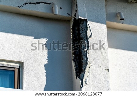 The outer wall of a building that has deteriorated and the reinforcing bars are exposed,