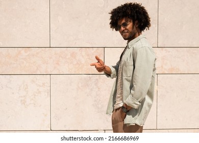 Outgoing Black man outdoor. African American man in casual clothes and sunglasses walking on sunny day. Portrait, city life concept