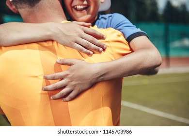 Outgoing child hugging dad after tennis game on modern field - Powered by Shutterstock