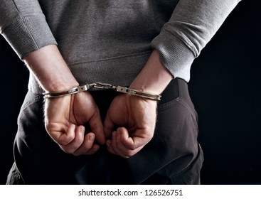 Outlaw's hands locked in handcuffs isolated on black - Shutterstock ID 126526751