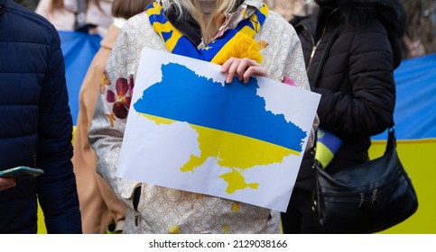Outline of Ukraine. Protester holding a sign with Ukrainian flag map. Demonstration against a war and Russia invasion on Ukraine. Russian attack protest, manifestation. - Shutterstock ID 2129038166