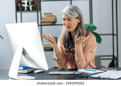 Outraged Annoyed Beautiful Asian Mature Woman, Business Lady Or Manager, Looks At Computer In Confusion, Shouts, Receives Unexpected News, Fails The Deal, Gestures, Sits At The Table In The Office