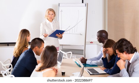 Outraged Mature Female Boss Standing Near Whiteboard In Meeting Room, Expressing Dissatisfaction With Work Of Subordinates
