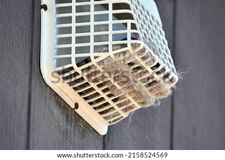 An outside dryer vent shown with considerable lint and debris which could cause a fire 