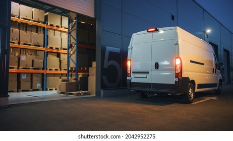 Outside Of Logistics Distributions Warehouse And Delivery Van Ready To Ride. Truck Delivering Online Orders, Purchases, E-Commerce Goods, Wholesale Merchandise. Evening Shot With Stop Lights On.