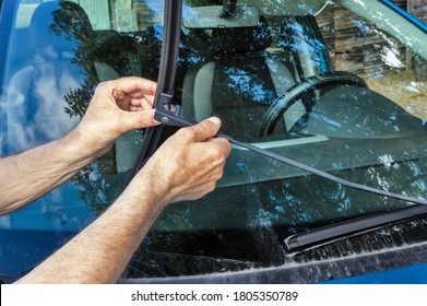 Outside, A Man Replaces A Car Windshield Wiper