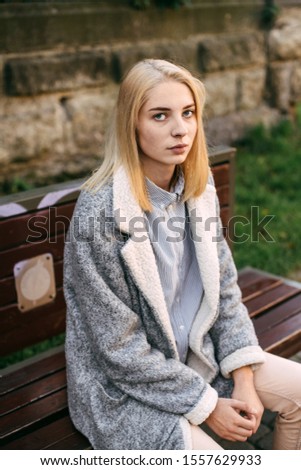 outside portrait of pretty blond in grey coat looking in camera
